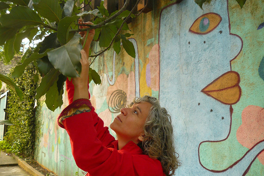 Fernanda Mascarenhas recolhendo folhas de abacateiro na calçada
