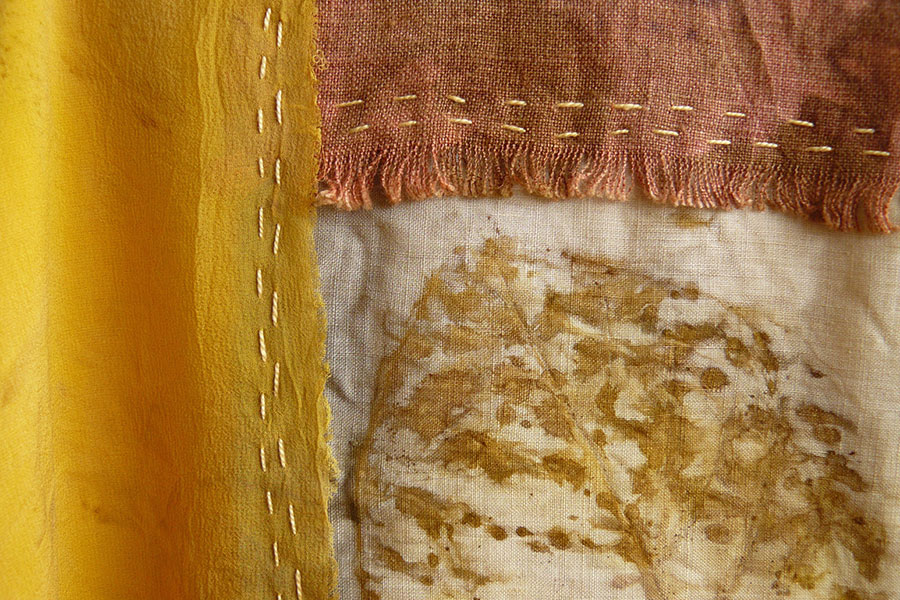 Detalhe da obra de arte têxtil Hagoromo mostrando tingimento natural amarelo com macela e folha de pixuruca